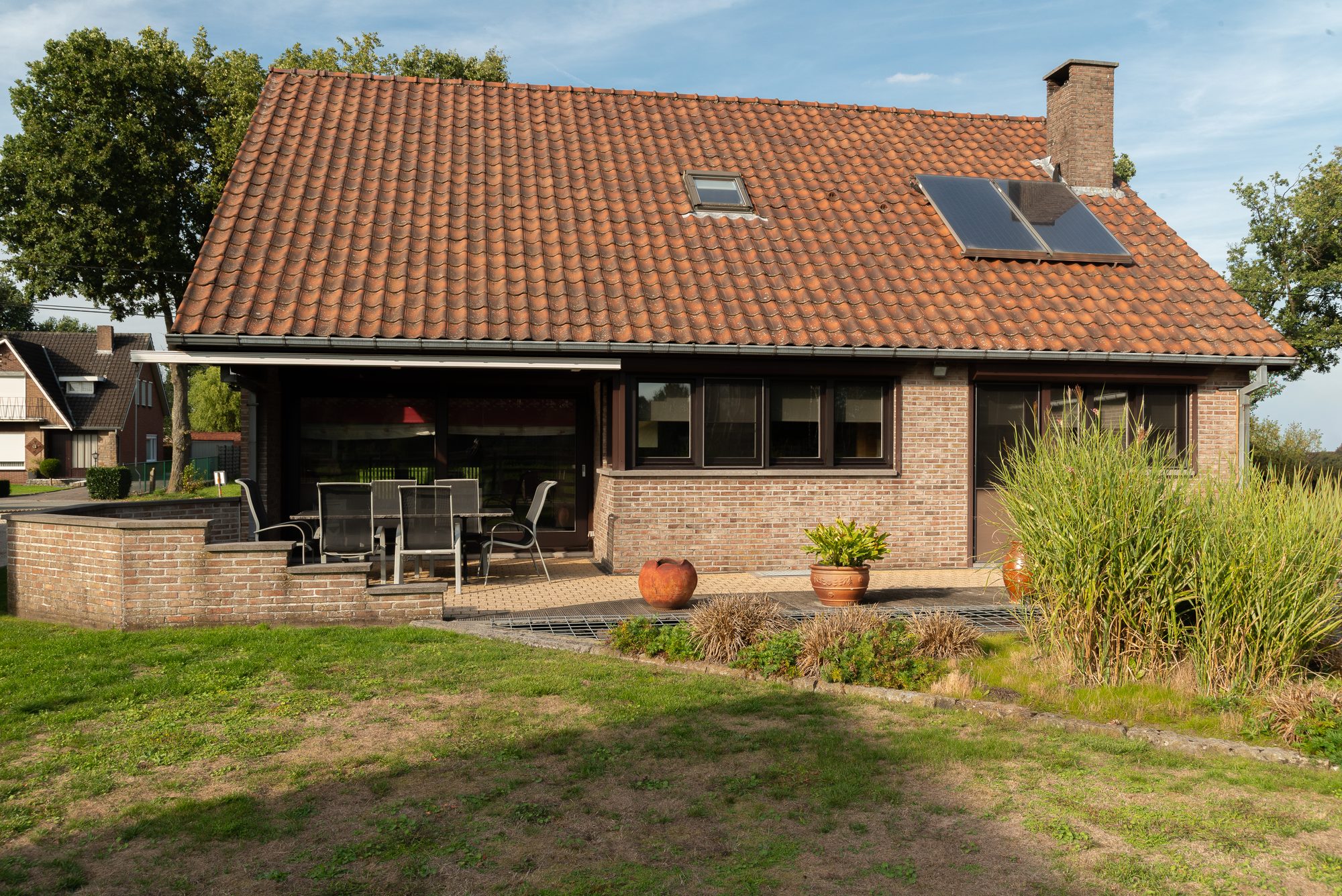 De achtergevel van de woning met terras en ruime tuin
