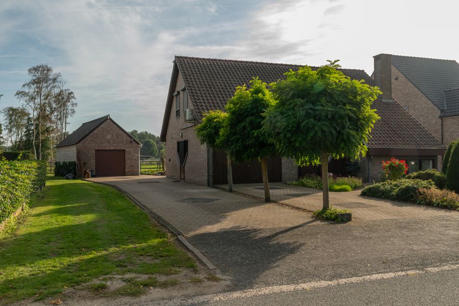 Twee garages — één ingebouwd, één vrijstaand — aan een brede oprit in klinkers